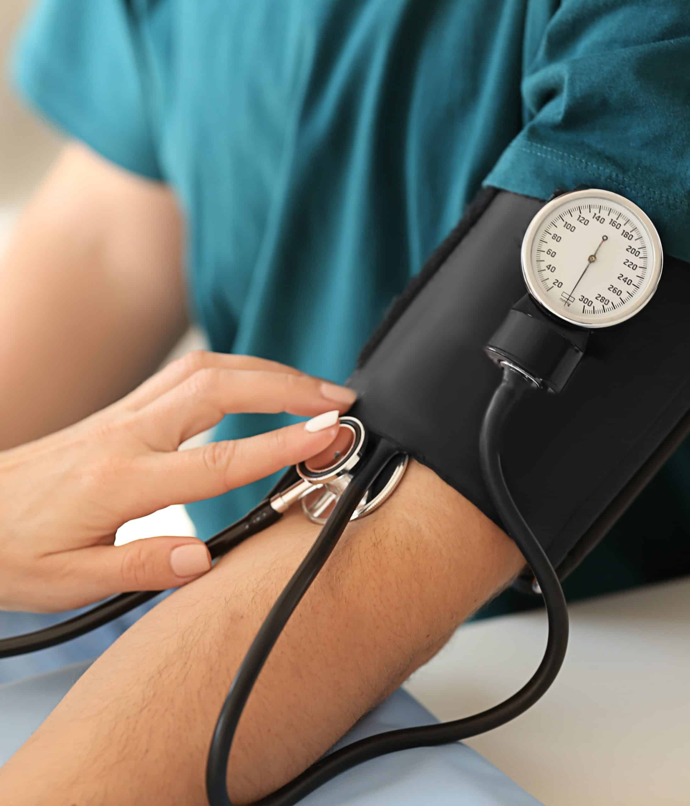 Medical professional measuring blood pressure with sphygmomanometer on patient's arm, emphasizing healthcare, blood pressure monitoring, and medical care in the Gulf Coast region.