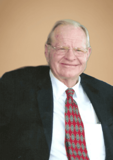 Senior businessman in formal suit smiling, representing Gulf Coast business leadership and economic growth.
