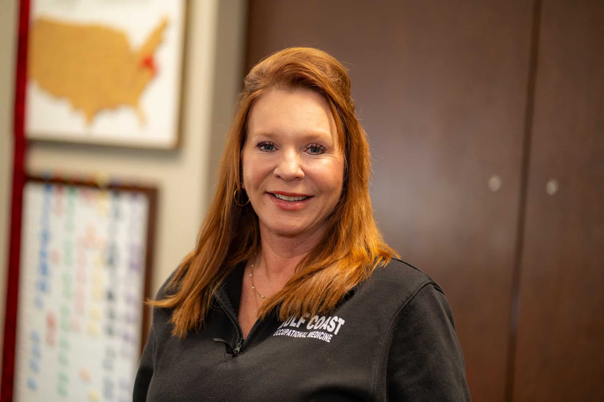 Gulf Coast healthcare professional smiling in a medical office, promoting occupational medicine services in the Gulf Coast region.